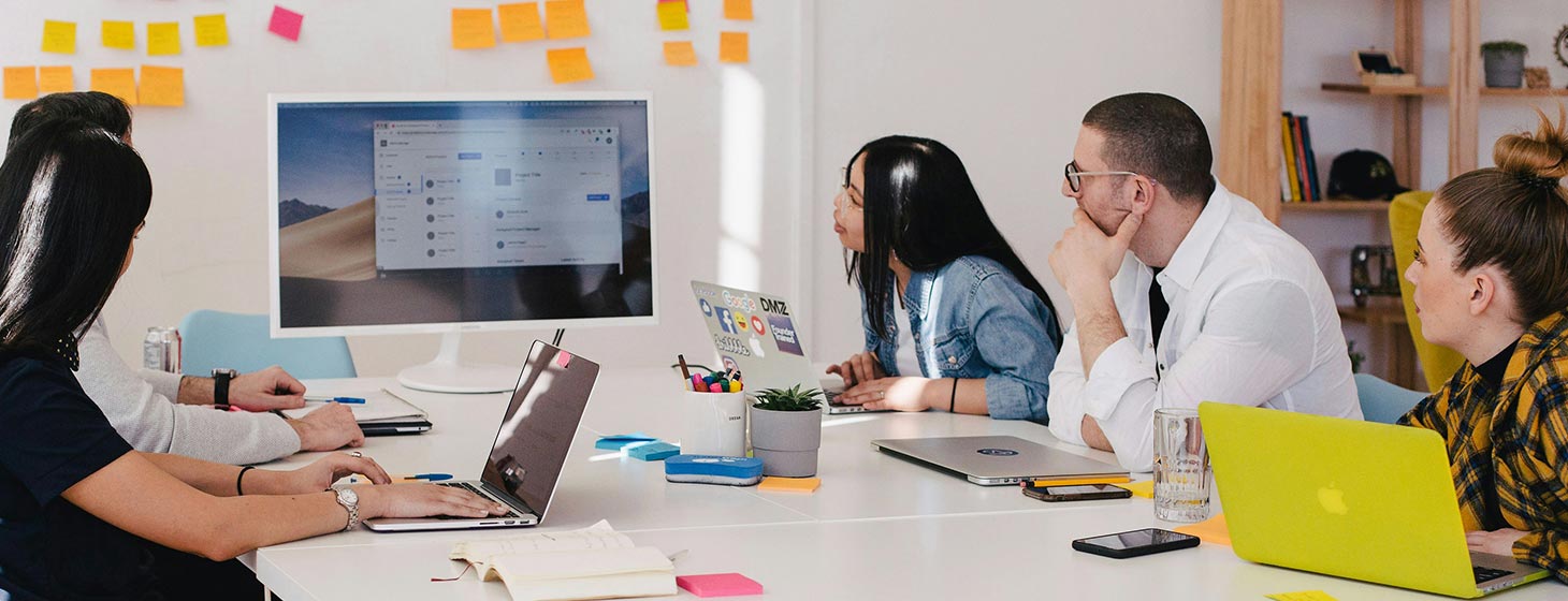 Image of project managers and developers looking at a screen discussing a project, 5 people in total.
